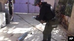 Imagen tomada de un video aficionado en la que aparece un supuesto investigador de la ONU examinando un cartucho en Moadamiyeh, en las afueras de Damasco.
