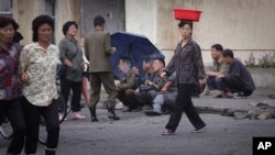 지난 6월 북한 원산의 한 도로 변에서 주민들이 담배를 피우고 있다.