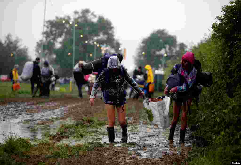 Para peserta acara perayaan Festival Glastonbury membawa barang miliknya saat mereka tiba di Worthy Farm di Somerset, Inggris.