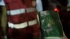 FILE - A rescuer holds a waterlogged Pakistani passport as bodies of migrants who drowned off the coast of Zuwara, Libya, are collected, Aug. 27, 2015.