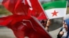 Members of a Turkish pro-government aid group, carrying Syrian and Turkish flags, wait for the departure of trucks carrying humanitarian aid destined for Idlib, Syria, in Istanbul, Sept. 10, 2018. The convoy of 20 vehicles will attempt to reach Syria to deliver basic needs. 