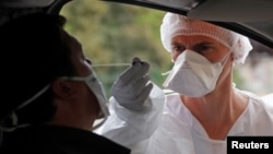 Un trabajador de la salud realiza una prueba del coronavirus en un puesto de auto-servicio en Laval, Francia.