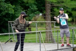 Susan Shin, left, catches a fish while fishing with her husband, Chris, April 20, 2020, at Sheldon Lake State Park in Houston. Texas Gov. Greg Abbott ordered state parks to reopen Monday.