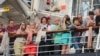 អ្នកដំណើរតាមនាវា Westerdam ឈរមើលការចាកចេញរបស់អ្នកដំណើរមួយចំនួន កាលពីព្រឹកថ្ងៃសុក្រ ទី១៤ ខែកុម្ភៈ ឆ្នាំ២០២០។ (ស៊ុន ណារិន/VOA)