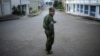 A Burma policeman uses his mobile phone as he patrols a street in Namteuk, neighboring China's border town of Mangka, Burma, September 3, 2009.