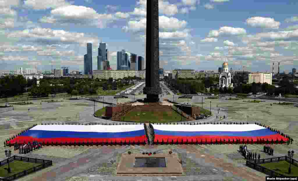 Para kadet dari Kementerian Darurat Rusia memegang bendera terbesar Rusia menjelang perayaan&nbsp; &#39;Hari Rusia&#39; di Moskow.