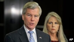 El exgobernador Bob McDonnell habla con la prensa mientras su esposa Maureen escucha atrás.