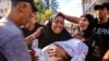A woman mourns as she holds the shrouded body of her child who was killed during an Israeli strike on a school housing displaced Palestinians in Gaza City, Sept. 21, 2024.