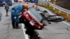 A worker looks at a car stuck on a cracked road in the aftermath of an earthquake, near Anamizu, Japan, Jan. 3, 2024.