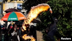 FILE - An anti-government demonstrator throws a petrol bomb toward Tsim Sha Tsui Police Station during a protest in Hong Kong, Oct. 20, 2019.