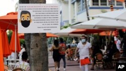 Un rótulo informa sobre el requerimiento de usar mascarillas al estar en áreas públicas en Miami Beach. Los infractores reciben una multa de 50 dólares, en un esfuerzo por controlar el avance del virus.