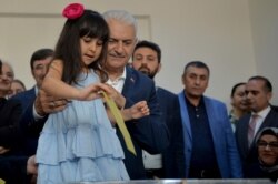 Binali Yildirim, mayoral candidate for Istanbul from Turkey's ruling Justice and Development Party, AKP, holds his granddaughter as she casts her grandfather's ballot at a polling station in Istanbul, June 23, 2019.