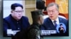 A South Korean marine passes by a TV screen showing file footage of South Korean President Moon Jae-in and North Korean leader Kim Jong Un, left, during a news program at the Seoul Railway Station in Seoul, South Korea, April 18, 2018.