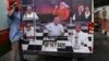 A journalist talks on his mobile phone next to an outdoor broadcasting vehicle plastered with portraits of Indian political leaders, in Bangalore, India, May 15, 2018.