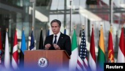 U.S. Secretary of State Antony Blinken, right, and NATO Secretary General Jens Stoltenberg wear protective masks as they prepare to stand with NATO foreign ministers during a meeting of NATO foreign ministers in Brussels, March 23, 2021. 