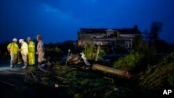 Los trabajadores de servicios públicos examinan los daños de la tormenta a lo largo de Cothran Road, el miércoles 8 de mayo de 2024, en Columbia, Tennessee.