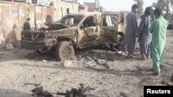 Residents look at an Army vehicle which was damaged during battle between Afghan security forces and Taliban in Farah province, Afghanistan, May 16, 2018. 
