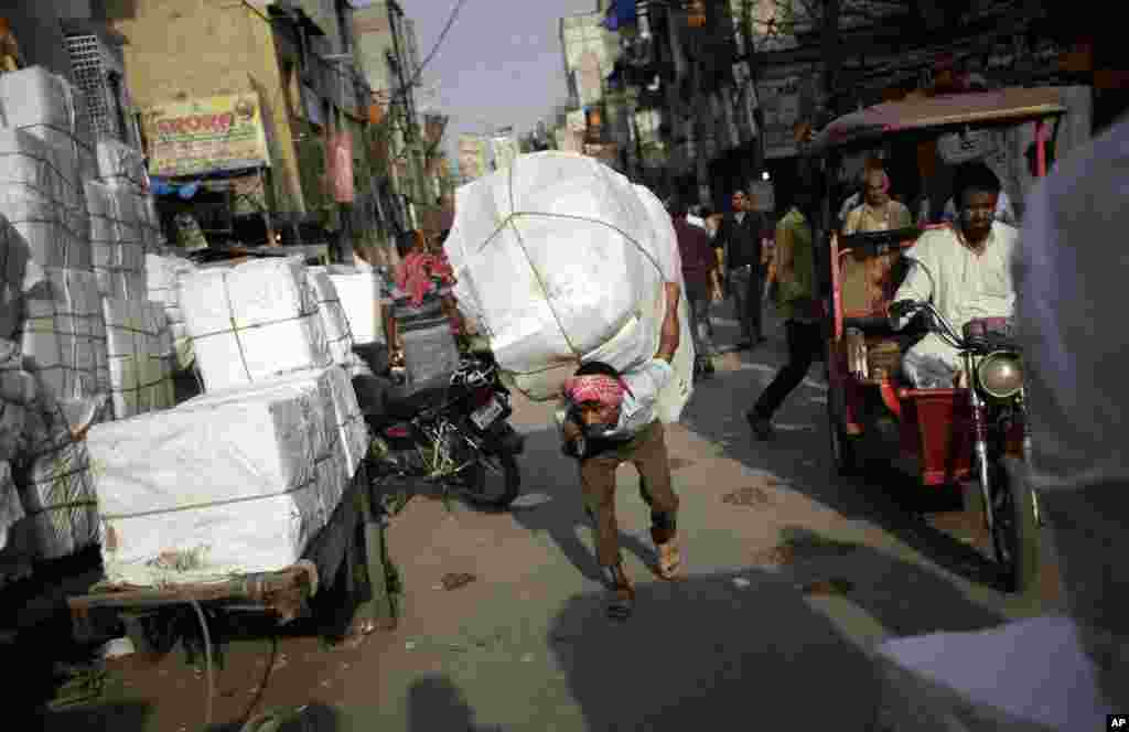 Pekerja India menggendong barang bawaannya melewati jalanan India yang ramai di &nbsp;sore hari yang panas di New Delhi, India.