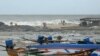 People stand ashore while waves lash over the Kovalam beach as cyclone Michaung is expected to make landfall, in Chennai on Dec. 3, 2023. 