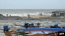 People stand ashore while waves lash over the Kovalam beach as cyclone Michaung is expected to make landfall, in Chennai on Dec. 3, 2023. 
