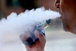 FILE - In this Aug. 28, 2019, file photo, a man exhales while smoking an e-cigarette in Portland, Maine.