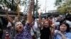 Voters hold their identification cards and the chains that held the gate of the polling station closed, as they demand the right to vote during general elections in Bangkok, Thailand, Feb. 2, 2014.