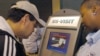 FILE - Department of Homeland Security official (r) assist a passenger (l) as he scans his fingerprint on a machine, part of the exit process at Hartsfield-Jackson Atlanta International Airport in Atlanta.
