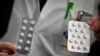 FILE - In this photo taken Feb. 26, 2020, medical staff at the IHU Mediterranee Infection Institute in Marseille show packets of Nivaquine (chloroquine) and Plaquenil (hydroxychloroquine).