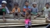 In this March 17, 2017, image made from video, Rosmaida Bibi, center foreground, suffering from severe malnutrition, sits on a pile of bamboo trees with other children at the Dar Paing camp, north of Sittwe, Rakhine state, Myanmar.