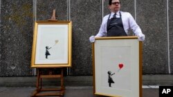 Dua versi "Girl with Balloon" (Anak perempuan dengan balon) yang ikonik, karya seniman jalanan anonim Banksy, ditampilkan selama sesi foto di dekat salah satu lokasi asli tempat karya seni itu muncul, di Southbank di London, Inggris (foto: ilustrasi).