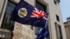 FILE - A flag of Hong Kong is waved in front of a placard during a protest against Hong Kong's deteriorating freedoms, outside China's embassy, in London, Britain, July 31, 2020. 