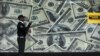 FILE - A security guard walks past a montage of old U.S. dollar bills outside a currency exchange bureau in Kenya's capital Nairobi, July 23, 2015. WorldRemit, a British-based money transfer company, recently launched a new digital service in four East African countries.