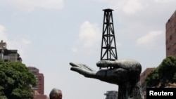 Un hombre camina junto a una escultura frente a un edificio de la compañía petrolera estatal de Venezuela PDVSA en Caracas, Venezuela. 17 de mayo de 2019. 