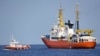An Italian Coast Guard boat, left, approaches the French NGO "SOS Mediterranee" Aquarius ship, in the Mediterranean Sea, June 12, 2018. Italy dispatched two ships Tuesday to help take 629 migrants stuck off its shores on the days-long voyage to Spain.