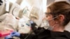 Kylene Karnuth, a clinical lab scientist, works with coronavirus samples as researchers begin a trial to see whether malaria treatment hydroxychloroquine can prevent or reduce the severity of the coronavirus disease (COVID-19), at the University of…