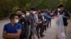 FILE - Unaccompanied minors from Central America line up to be transported by U.S. Customs officials, after crossing the Rio Grande into the United States from Mexico on rafts, in Penitas, Texas, March 26, 2021.