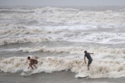 Residentes locales en Galveston, Texas, surfean en las altas olas creadas por la tormenta tropical Hanna. Julio 26 de 2020.