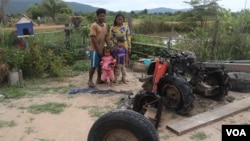 ក្រុម​គ្រួសារ​របស់​អ្នកស្រី គា ទាវ ឈរ​នៅ​ក្បែរ​គោយន្ត ដែល​ត្រូវ​បាន​ដុតចោល កាល​ពី​ថ្ងៃ​ទី​៥ ខែ​សីហា ឆ្នាំ២០២០ ក្នុង​ឃុំ​ស្វាយ​ស ស្រុក​ក្រគរ ខេត្ត​ពោធិ៍សាត់។ (ស៊ុន ណារិន/វីអូអេ)