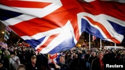 FILE - A man waves a British flag in London, January 31, 2020.