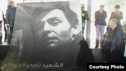 Friends hold up a poster of Syrian filmmaker Naji Jerf, who was gunned down Dec. 27, 2015, in Turkey. 