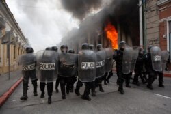 La policía antimotines forma un cordón frente al edificio del Congreso en Ciudad de Guatemala, parte del cual fue incendiado por manifestantes el sábado 21 de noviembre de 2020.